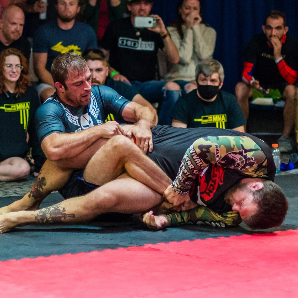 Two men at a grappling tournament performing leg locks