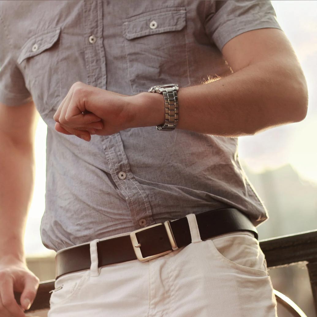 Extreme upclose of a man's chest. He's finely dressed in a hurry looking at his watch.